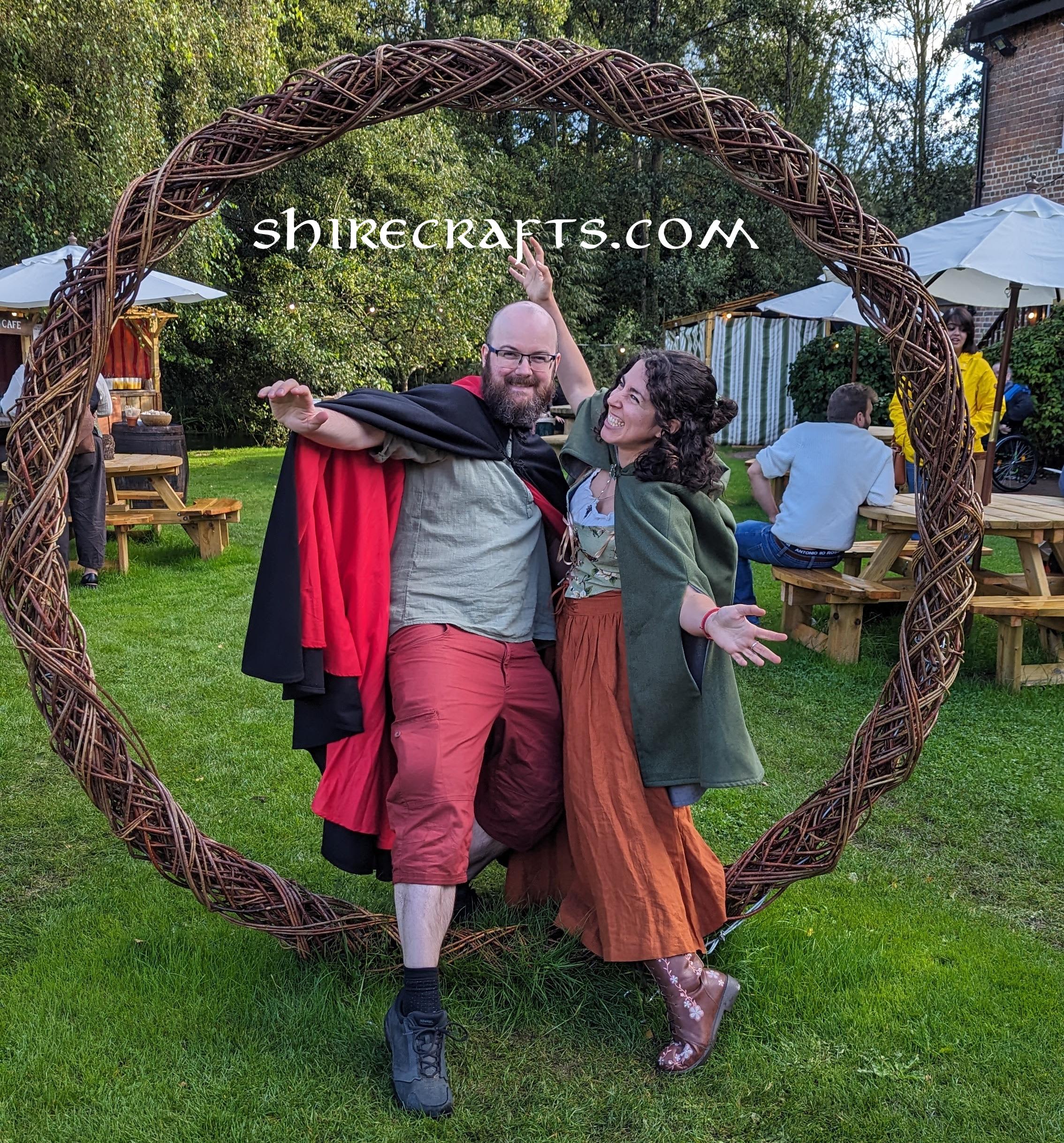 Two people dressed as hobbits jumping through a large wicker ring